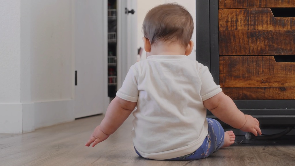 Beba sedi na podu okrenuta leđima