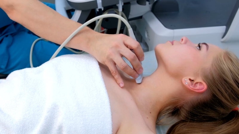 Trudnica leži na pregledu dok lekar ultrazvučnom sondom proverava štitnu žlezdu u predelu vrata